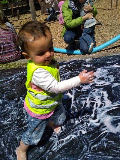 toddler dancing on a slip-and-slide covered in foam