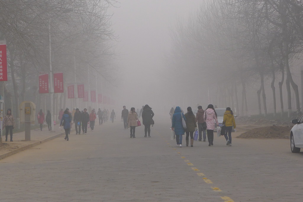 Thick smog with pedestrians walking down the street